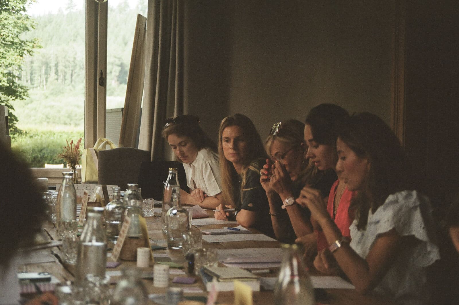A long wooden table covered with agenda pages, stickers and washi tape, with guests writing and talking