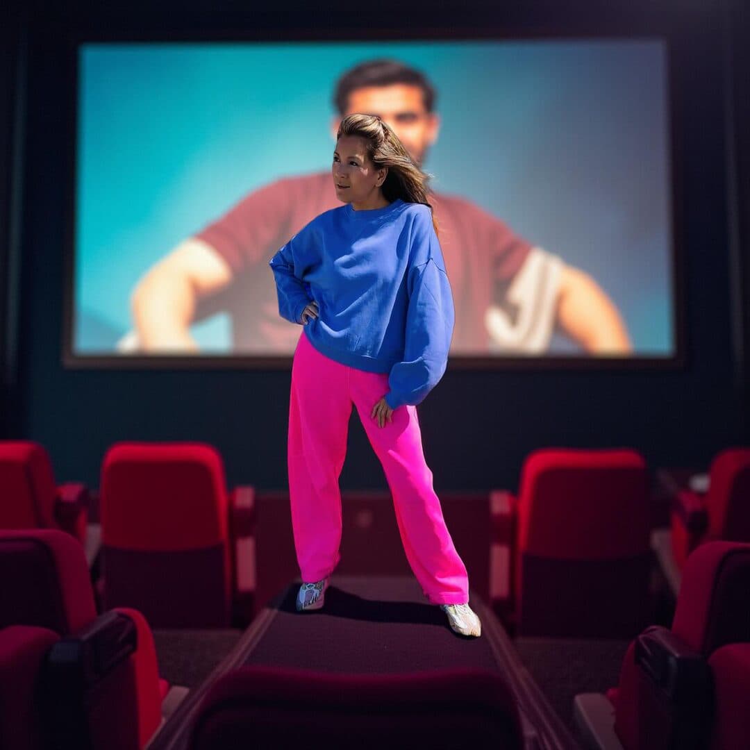 Marie-Ange standing in a cinema, in a blue sweater and pink trousers